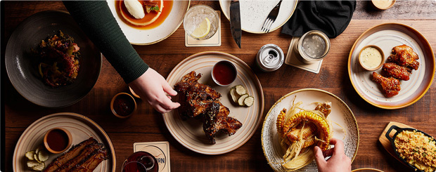 Group meal captured from above, showing various people enjoying BBQ ribs and fried chicken at Longhorn Smokehouse.