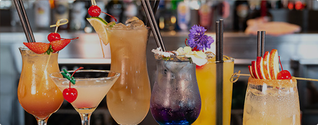 Assortment of colourful cocktails adorned with fruits and flowers on the Green Room Bar counter.